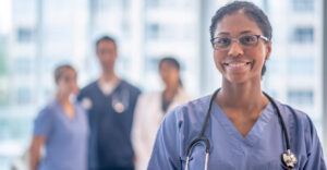 nurse stands and smiles with other nurses in background